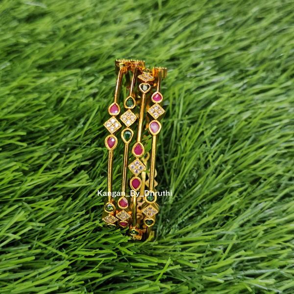 Four gold bangles with pink, green, and red gemstone accents, displayed on a green grass background.
Ruby Pink & Emerald Green Micro-Gold Plated Temple Bangles